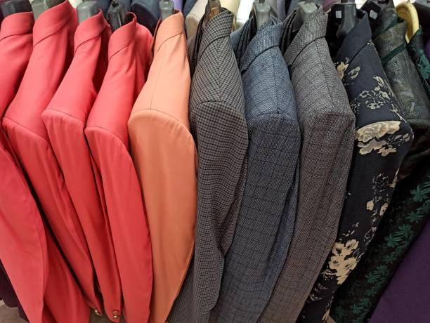 A row of antique clothing, including colorful jackets and patterned blazers, hanging on a rack.