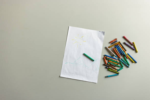 Crayons and a drawing on paper highlight the topic of removing crayon marks from walls without damage.